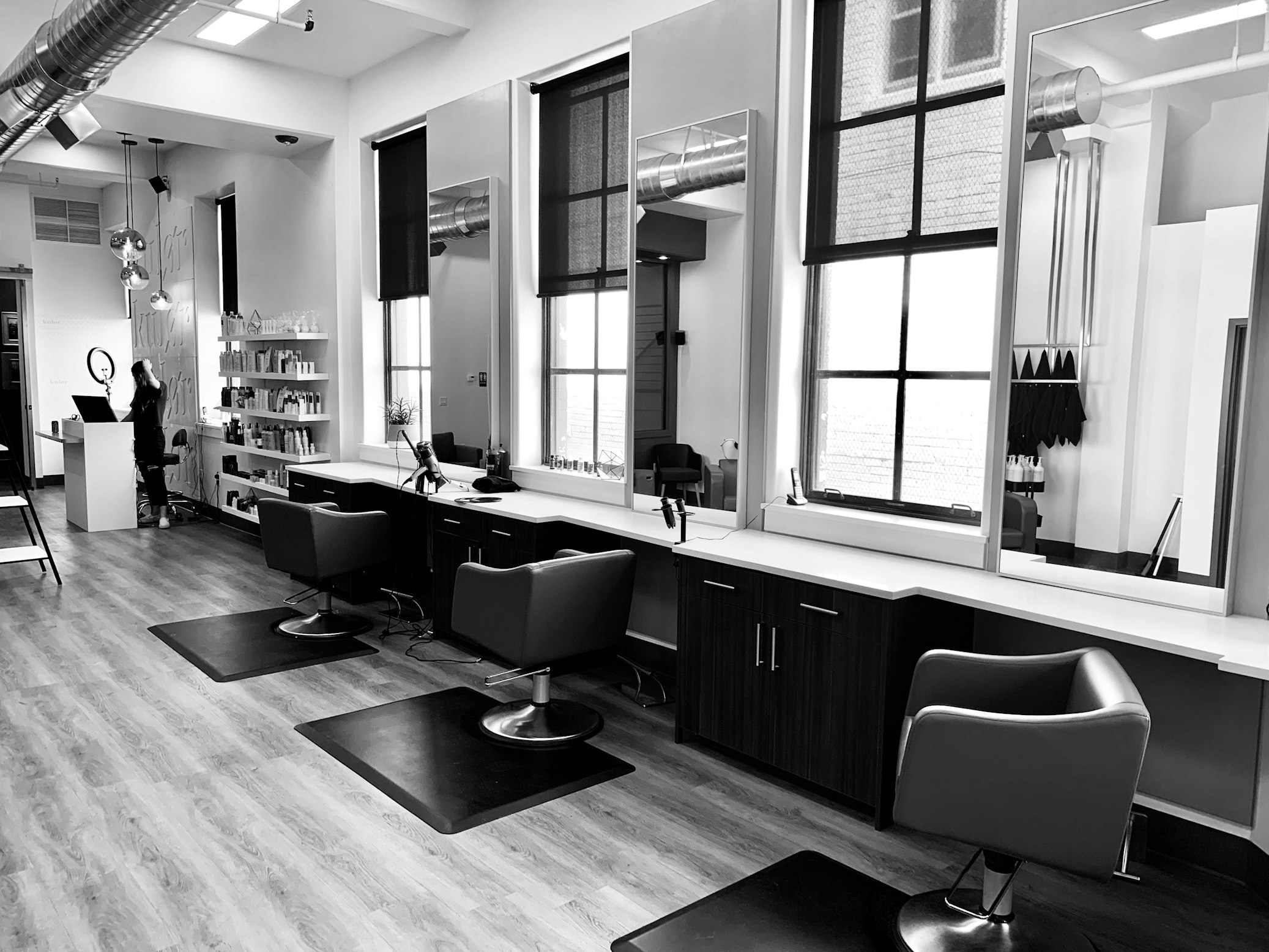 Bustling modern salon with stylists working and customers getting hair services in a bright, welcoming environment